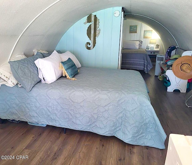 bedroom with a textured ceiling, vaulted ceiling, and hardwood / wood-style flooring