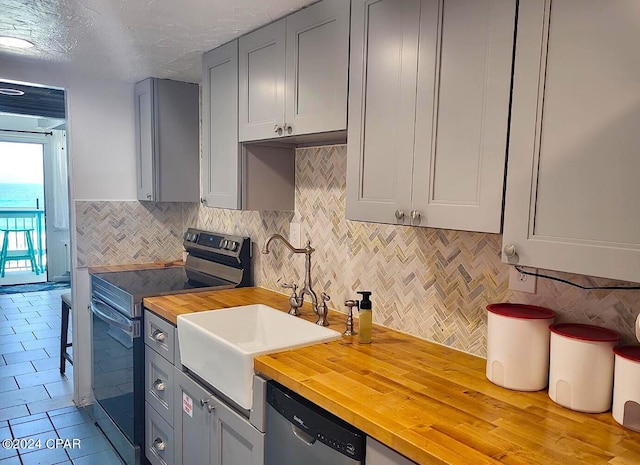 kitchen featuring gray cabinetry, wood counters, sink, and stainless steel appliances