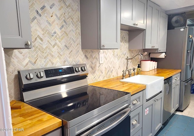 kitchen with gray cabinets, stainless steel appliances, butcher block counters, and tile patterned floors