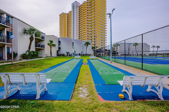 view of home's community featuring a lawn and tennis court