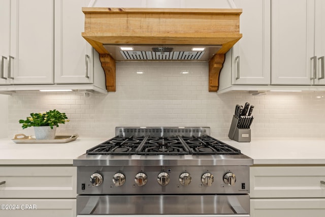 kitchen featuring tasteful backsplash, stove, and white cabinets