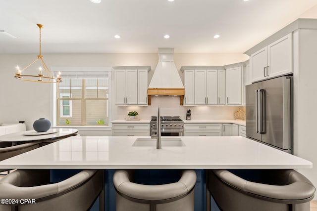 kitchen featuring pendant lighting, custom exhaust hood, high quality appliances, sink, and a notable chandelier