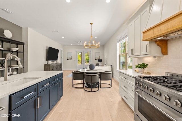 kitchen featuring blue cabinetry, sink, high end stove, white cabinets, and custom range hood