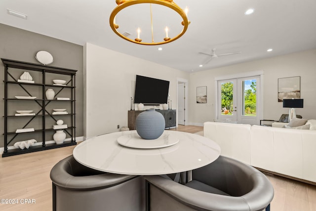 dining room featuring ceiling fan with notable chandelier and light hardwood / wood-style floors