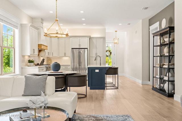 living room with an inviting chandelier, light hardwood / wood-style flooring, and sink