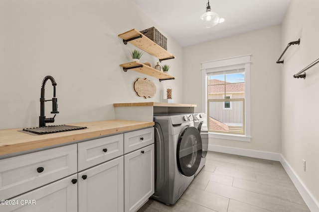 washroom with cabinets, sink, and washer and dryer