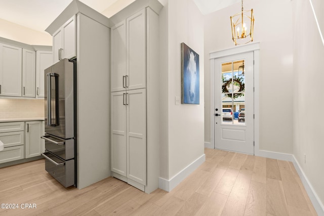 kitchen featuring high end fridge, decorative light fixtures, decorative backsplash, a notable chandelier, and light hardwood / wood-style floors