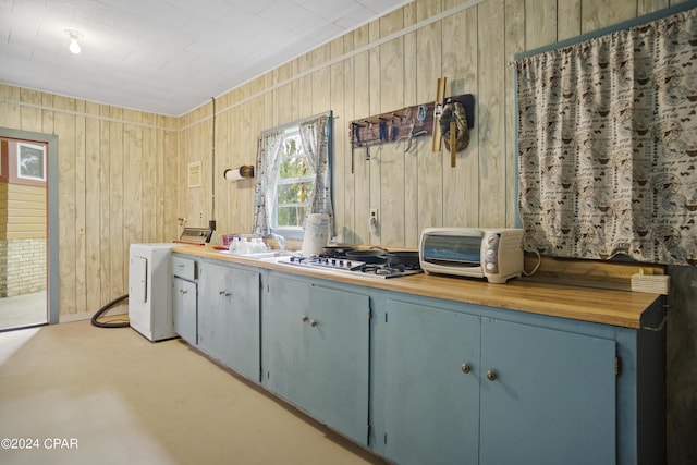 13272 NW State Road 20, Bristol, FL 32321 - kitchen with washer / clothes dryer, gas cooktop, wood counters, wood walls, and blue cabinetry