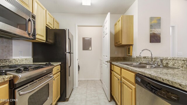 kitchen featuring light stone counters, appliances with stainless steel finishes, electric panel, and sink