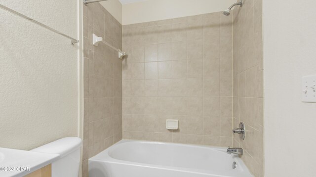 full bathroom featuring vanity, tiled shower / bath, and toilet