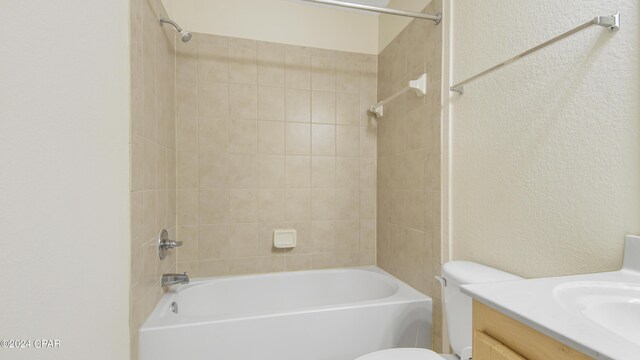 full bathroom featuring tiled shower / bath, vanity, and toilet