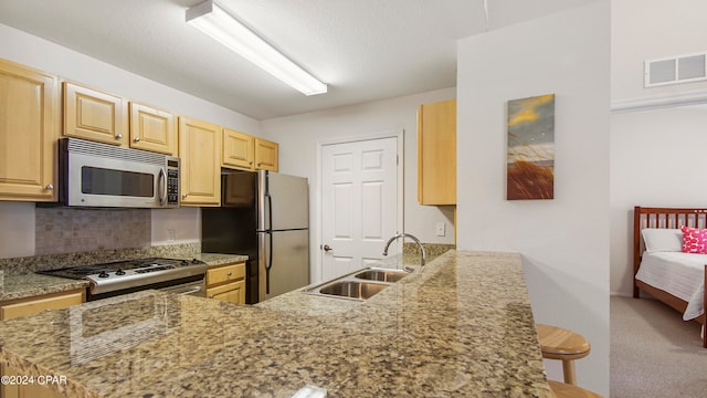 kitchen featuring a breakfast bar, light stone counters, sink, kitchen peninsula, and stainless steel appliances