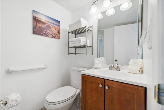 bathroom featuring a textured ceiling, vanity, and toilet