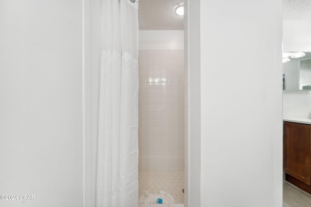 bathroom featuring vanity, a textured ceiling, and curtained shower