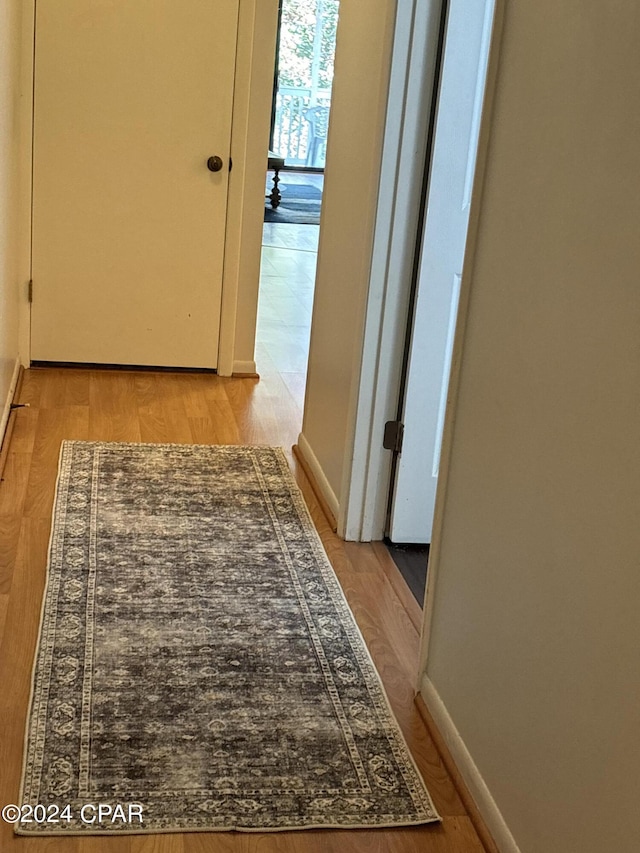 corridor with light wood finished floors and baseboards