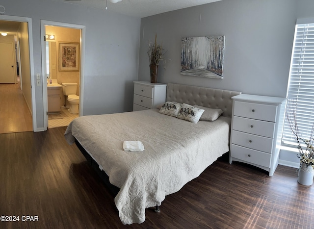 bedroom featuring dark wood-style floors, baseboards, and ensuite bathroom