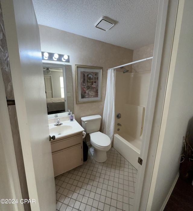 ensuite bathroom with shower / tub combo with curtain, toilet, a textured ceiling, vanity, and tile patterned flooring