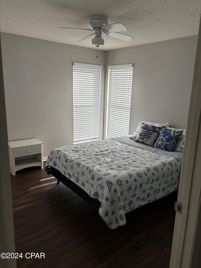 bedroom featuring dark wood-style flooring, ceiling fan, a textured ceiling, and baseboards