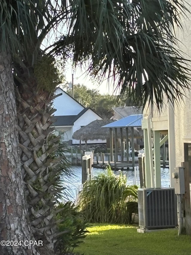 dock area featuring cooling unit, a water view, and a yard