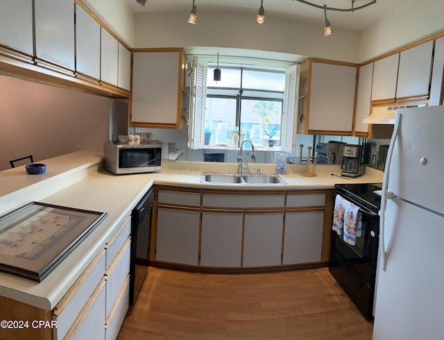 kitchen featuring white cabinets, light countertops, a sink, and black appliances