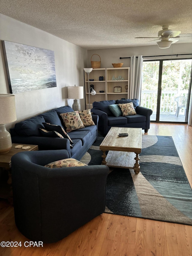 living room with ceiling fan, a textured ceiling, and wood finished floors