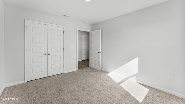 unfurnished bedroom with carpet, a closet, visible vents, and baseboards