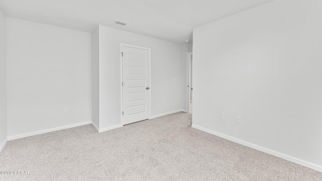 carpeted spare room featuring visible vents and baseboards