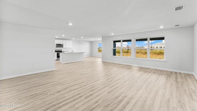 unfurnished living room featuring baseboards, light wood-style flooring, visible vents, and recessed lighting