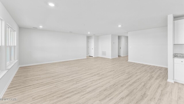 unfurnished living room with light wood-type flooring, baseboards, visible vents, and recessed lighting