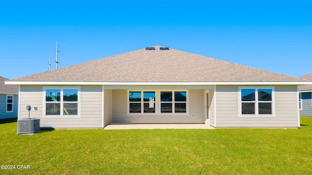 back of property featuring a shingled roof and a yard