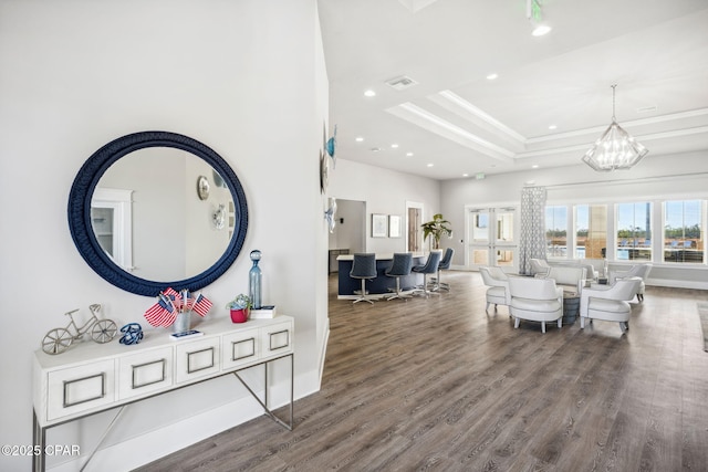 living room featuring recessed lighting, a notable chandelier, wood finished floors, visible vents, and a tray ceiling