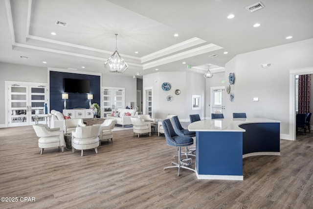 living area with french doors, wood finished floors, a raised ceiling, and visible vents