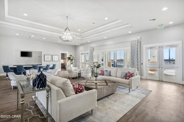 living room with recessed lighting, wood finished floors, visible vents, a tray ceiling, and crown molding