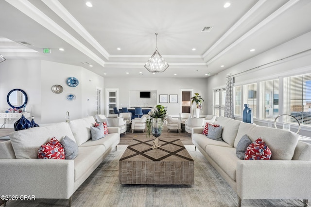 living area featuring ornamental molding, a raised ceiling, visible vents, and a notable chandelier