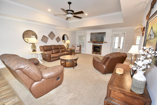 living room with ceiling fan, a raised ceiling, and crown molding