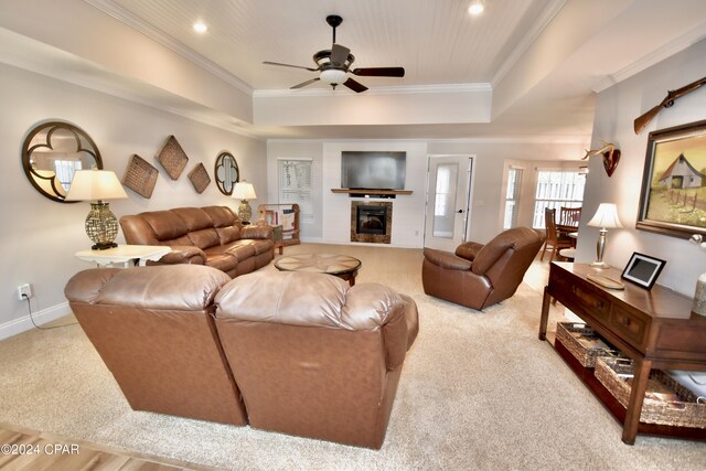 carpeted living room featuring ceiling fan, a raised ceiling, and ornamental molding