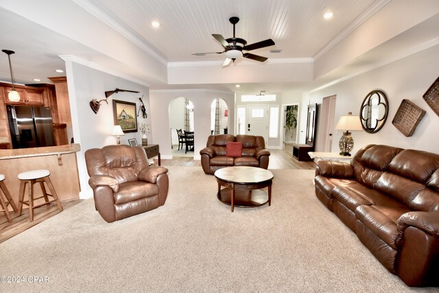 living room featuring light wood-type flooring, crown molding, ceiling fan, and a raised ceiling