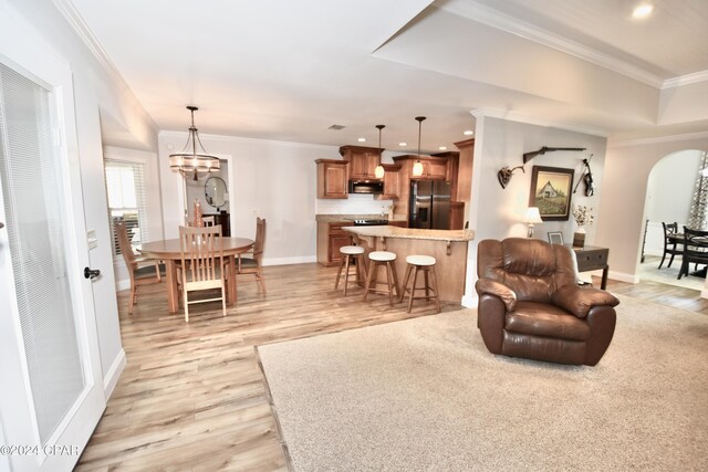 living room with crown molding, light hardwood / wood-style floors, and a chandelier