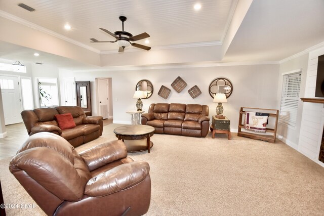 living room with ornamental molding, a raised ceiling, ceiling fan, and light colored carpet