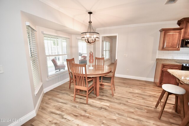 dining space with light wood-type flooring, ornamental molding, and a notable chandelier