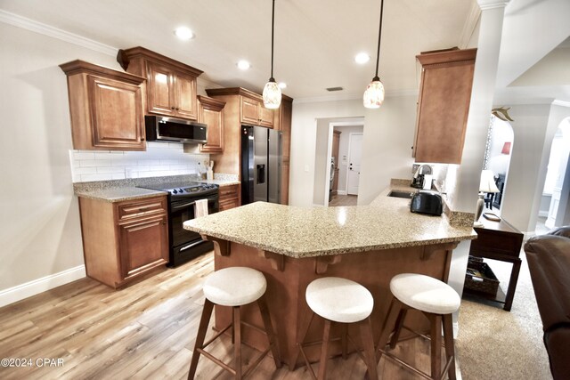 kitchen featuring stainless steel appliances, kitchen peninsula, a kitchen breakfast bar, and light hardwood / wood-style flooring