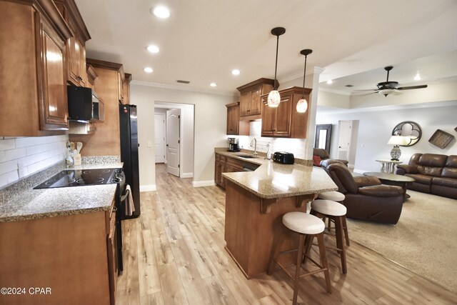 kitchen featuring light hardwood / wood-style floors, kitchen peninsula, a breakfast bar area, pendant lighting, and ceiling fan