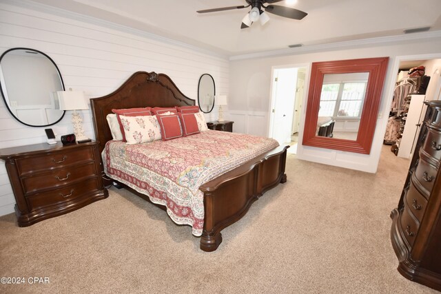 carpeted bedroom featuring ceiling fan, wood walls, ornamental molding, and a spacious closet