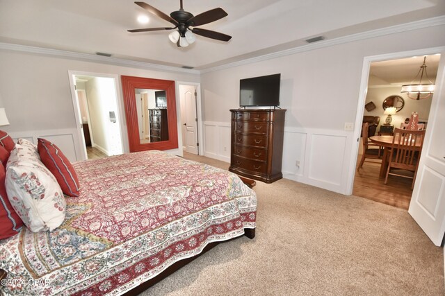 carpeted bedroom featuring ceiling fan with notable chandelier and crown molding