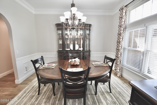 dining area with light hardwood / wood-style floors, ornamental molding, and an inviting chandelier