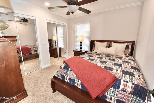 bedroom featuring ornamental molding, ceiling fan, light colored carpet, and multiple closets