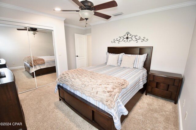 bedroom featuring light carpet, a closet, ceiling fan, and ornamental molding