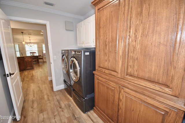 laundry area with washer and clothes dryer, cabinets, a notable chandelier, crown molding, and light hardwood / wood-style floors