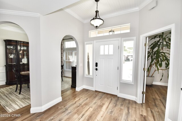 foyer entrance featuring wood-type flooring, plenty of natural light, and crown molding