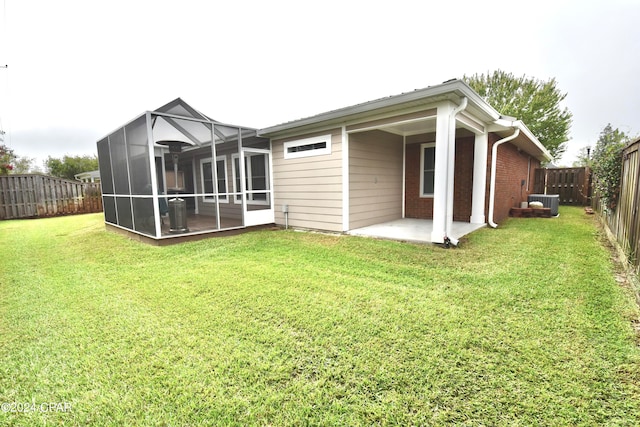 back of house with a sunroom, a patio area, central air condition unit, and a yard